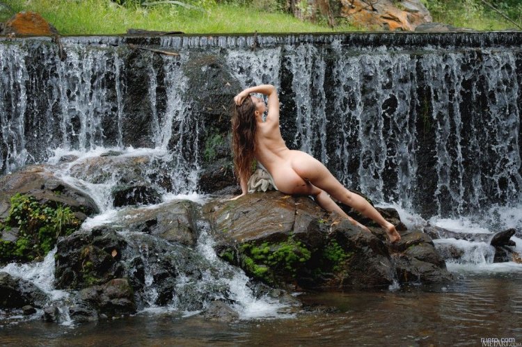 Nude girl under a waterfall