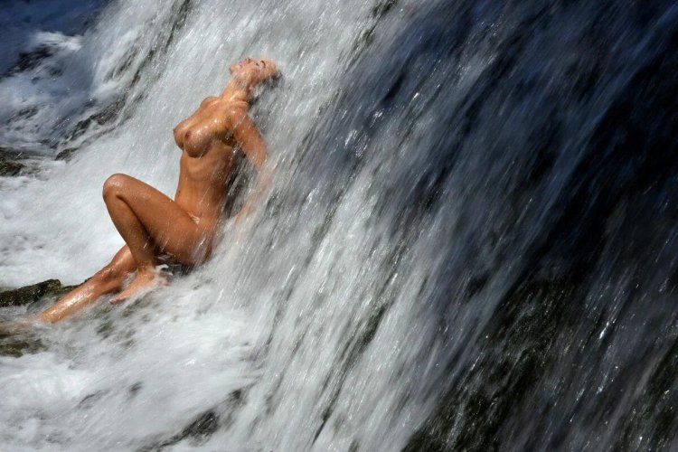 Naked women under a waterfall